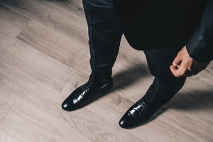 Man in black tuxedo suit with focus on black men's cap toe dress shoe